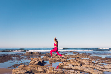 Woman wearing hot pink gym clothes exercising at the beach.