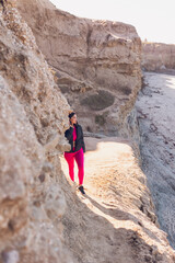 Woman wearing gym clothes walking on the beach cliffs in California.