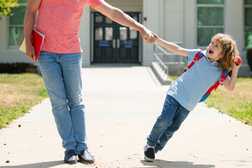Obraz premium Father and excited son walking trough school park.