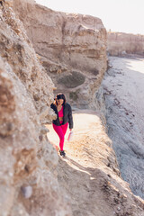 Obraz premium Woman wearing gym clothes walking on the beach cliffs in California.