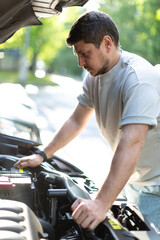 a man on a city street checks the operation of the car, looks under th