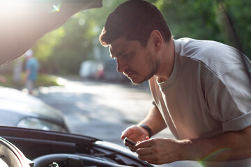 a man on a city street checks the operation of the car, looks under th