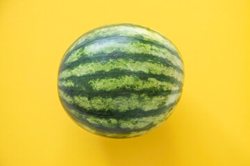 Green watermelon on yellow background top view