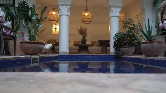 A tourist pass by a swimming pool in a luxury riad in Marrakech, Moroc
