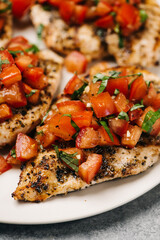 Closeup of grilled chicken breast with tomatoes and basil