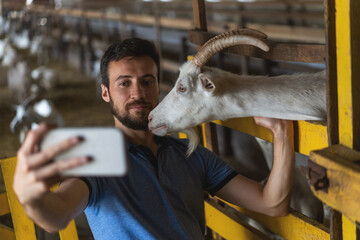 guy takes a selfie on the phone with a goat