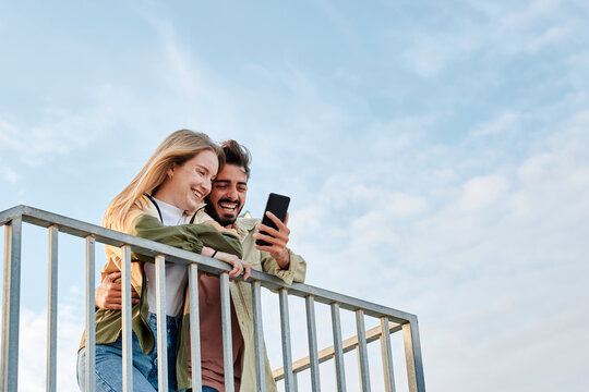 Young multiracial couple smiles while they are looking at a phone