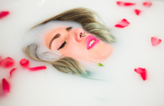Woman relaxing in a bathtub with milk and roses