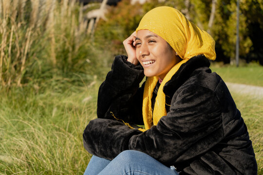 Young woman with breast cancer undergoing treatment. Smiling for the remission of the tumor and good news. Wear a yellow bandana or scarf to cover up the effects of chemotherapy. Concept Opti