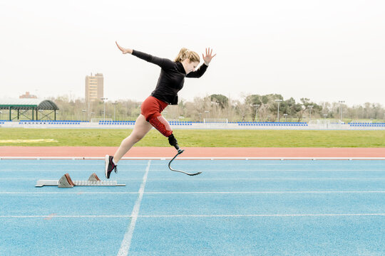 Sportswoman with prosthetic leg running near the starting blocks