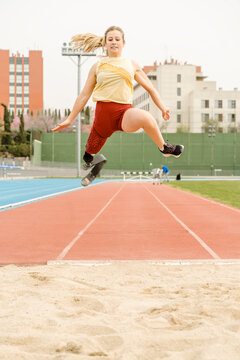 Handicapped sportswoman jumping on sand during workout