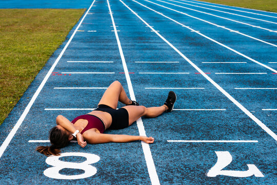 Tired female sprinter lying an athletics track