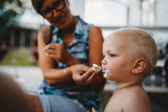 Adult feeding young child a popsicle cream ice cream outside in summer