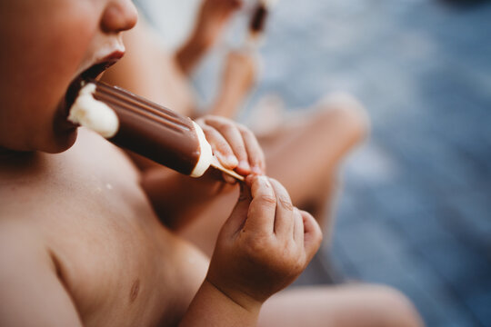 Close up of child hands holding and eating a chocolate cream popsicle