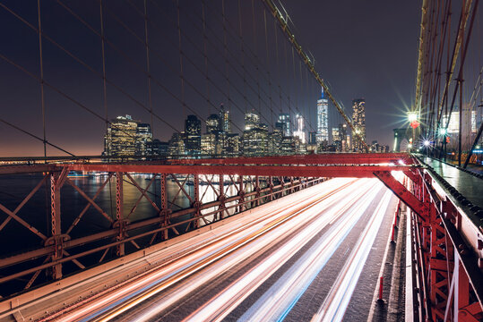 Cars driving on highway under suspension bridge in night city