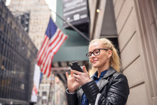 Cheerful woman using smartphone on urban city street