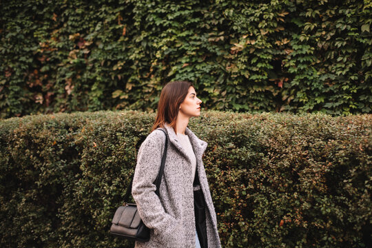Young woman walking in city against green plants