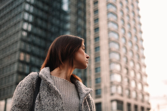 Thoughtful non-binary woman standing on street in city