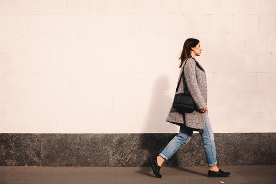 Side view of woman walking against wall in city