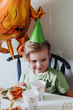 5 years boy playing in his room, wearing green t-shirt with dinosaurus print, having birthday