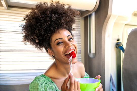Pretty African woman eating a healthy strawberry