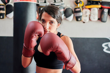 Woman in boxing gloves trains while looking at the camera