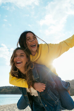 Girl giving a piggyback her friend outdoors