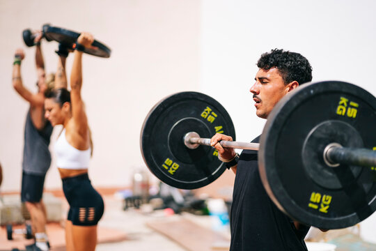 A group of sporty friends perform different exercise routines outdoors