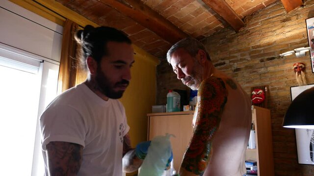 Tattoo artist cleaning a client's arm before starting tattooing.