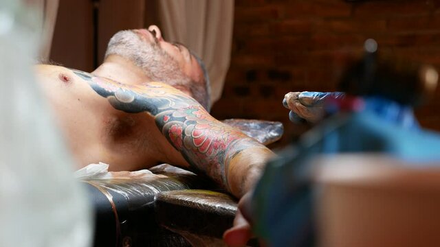 Close up of hands of an artist tattooing on a customer's arm.