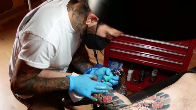 Aerial view of an tattoo artist working on a customer's arm.