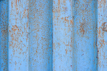 The texture of rusted metal painted in blue. Rough metal surface with rust. Rusty metal wall of a shipping container. Perfect for background and design.