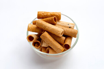 Thai crispy coconut rolls in glass bowl on white background.