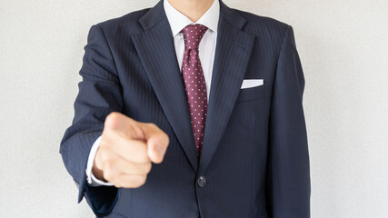 スーツ姿のビジネスマン。指をさす男性。