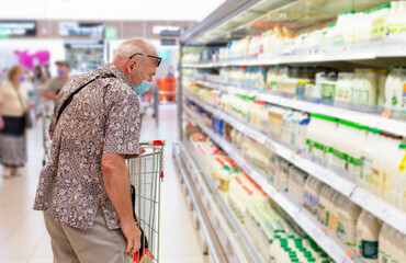 A man with a protective mask in the dairy department of a supermarket