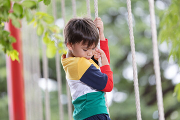 A boy wearing bright colored clothes playing rope hanging at playground and having fun healthy summer vacation activity.The concept of healthy lifestyle