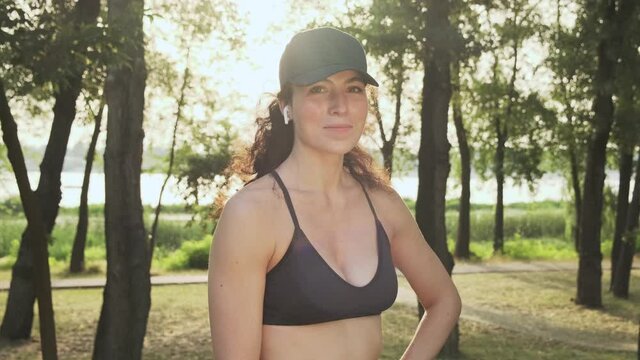 Portrait of a female jogger. Sports girl posing in a public park early in summer morning