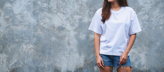 Closeup image of a young woman wearing blank white T-shirt and blue jean short pant standing in...