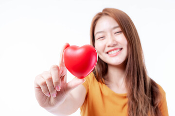 Portrait of smiling a beautiful Asian young woman holding red heart in hand on white background- Valentine day concept