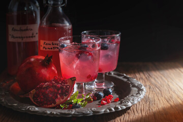 Fermented Pomegranate kombucha drink, Homemade probiotic black tea with fresh Pomegranate on metal tray in black background, healthy flavored drink