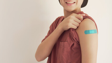 teen boy showing his arm with blue bandage after got vaccinated or  inoculation, child...