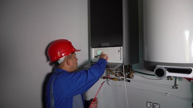Installation and setting the new gas boiler for hot water and home heating. Technician man servicing the house heating system. Smooth camera motion shot with gimbal.