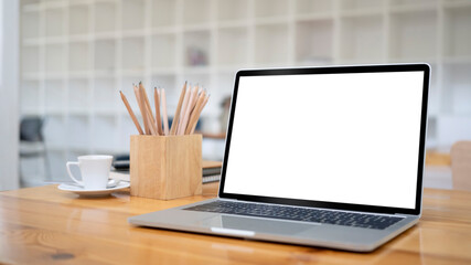 Close up laptop computer and pencil holder on wooden desk.