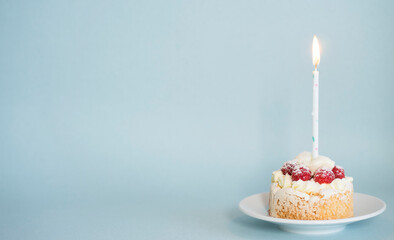 Appetizing cake in which a candle is stuck on a blue background