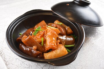 braised sea cucumber with oyster sauce in black hot clay pot in white background asian halal seafood menu