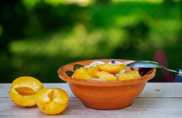 Bowl with oatmeal with apricots on a wooden table in the garden.