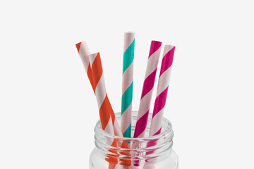 Collection of coloured paper straws in a glass jar isolated on white background, Eco-friendly concept.