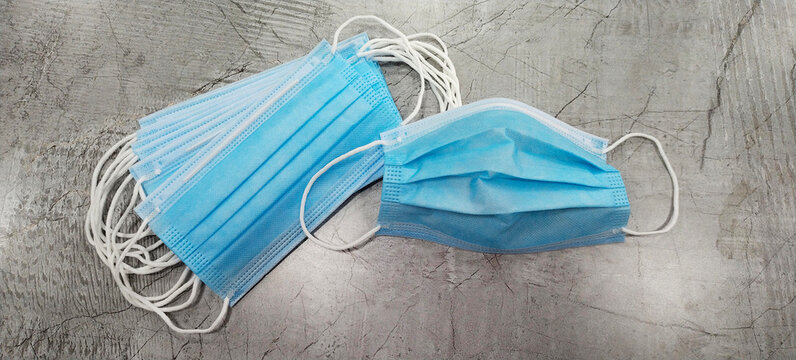 Blue colored surgical masks placed on a grey colored wooden background