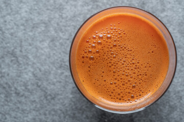 Glass of fresh carrot juice background, top view, close up