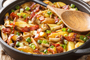 Rustic style fried potatoes with onions, mushrooms and bacon close-up in a frying pan. horizontal